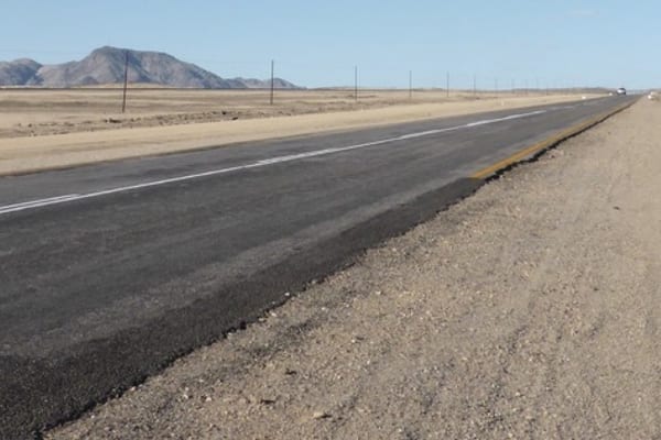 Een lege asfaltweg door een droog Zuid-Afrikaans landschap